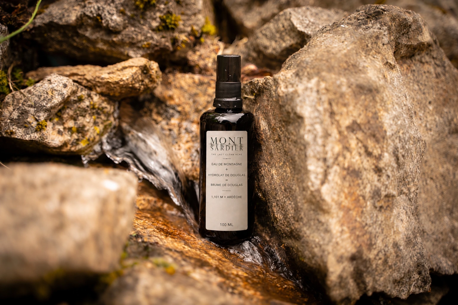 A labelled Mont Sardier mist bottle nestled among mountain rocks